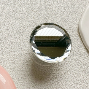 Macro view of a round diamond-cut mirror phone grip with a reflective faceted surface