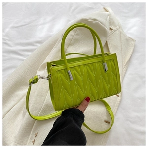 Close-up of fluorescent green quilted handbag showing V-shaped stitching and texture