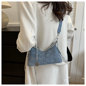 Detail view of a light blue denim underarm bag with silver chain and wide shoulder strap