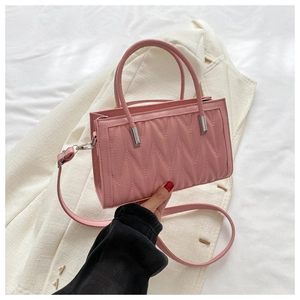 Detailed close-up of pink quilted crossbody bag with stylish V-shaped stitching pattern