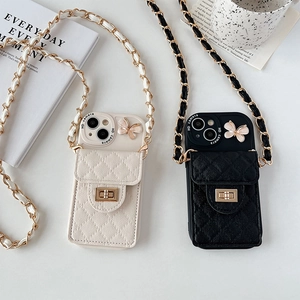 Close-up of quilted leather phone case with metal chain strap and butterfly charm detail