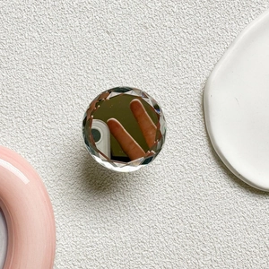 Macro detail of clear multifaceted crystal phone grip mirror showing light refraction