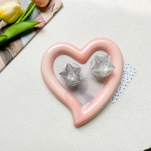 Detail showing two glittery star-shaped phone grips on a pink heart ceramic tray