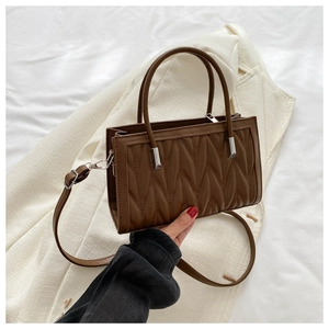 Detail of brown pleated matelassé leather handbag with adjustable shoulder strap and handles