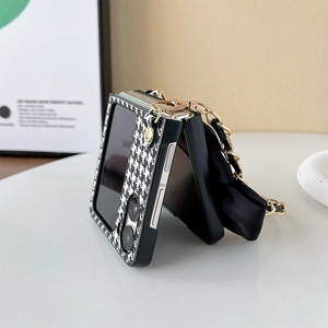 Detail of houndstooth folding phone case with a gold chain strap and silk bow charm