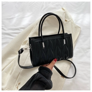 Detail of black quilted PU handbag with V-shaped stitching and silver hardware accents