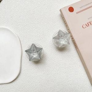 Star-shaped glitter phone grip shown on a minimalist French-style desk setup