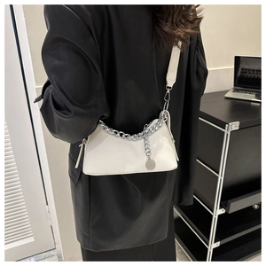 Modern white leather shoulder bag with bold silver chain worn by model in black jacket