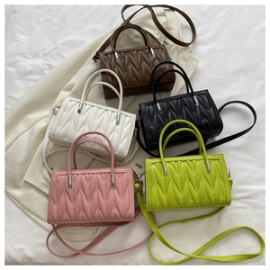 Flat lay of colorful wavy quilted crossbody bags in brown, white, black, pink and green