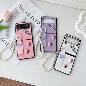 Pink and purple Samsung Z Flip 6 cases with pearl straps and cute 3D charms on a desk