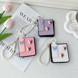 Close-up of Galaxy Z Flip 6 cases with pearl wristbands and 3D bunny tulip decor