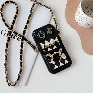 Detailed view of iPhone cross-body case with black leather quilt pocket and bear charm
