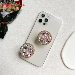 Gros plan de supports de téléphone scintillants en strass roses et blancs sur cuir blanc