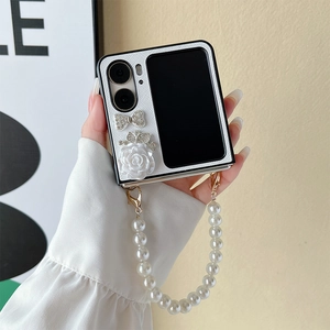 Close-up of white quilted flip phone case with camellia, crystal bow and pearl handle