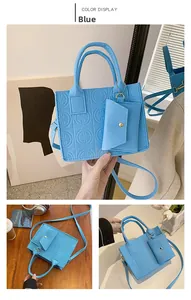 Détail d'un ensemble de sacs à main bleus gaufrés avec mini pochette et garniture dorée