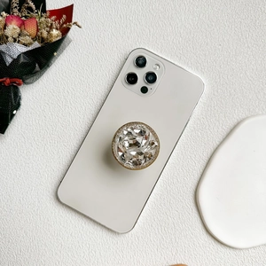 Support de téléphone doré luxueux avec strass étincelants sur smartphone blanc