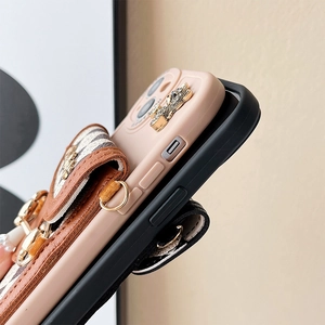 Macro shot of phone case wallet with bear charm and diamond pattern in pink and black