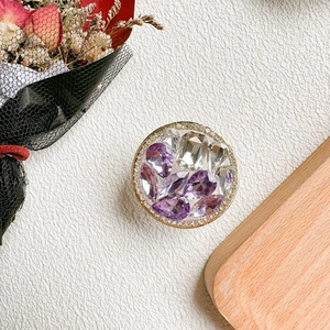 Vue détaillée d'un support de téléphone doré luxueux orné de strass violets et clairs