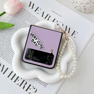 Detail view of purple Galaxy Z Flip 6 case with pearl strap and cute typography