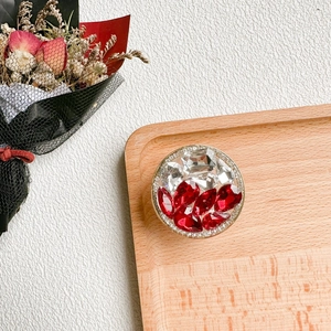 Détail d'un support de téléphone de luxe avec strass et cristal rouge sur plateau bois