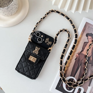 Detailed shot of black quilted phone case with gold bear charm and woven chain strap