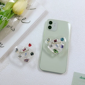 Detail of heart-shaped phone grip with colorful rhinestones and Diamonds gold lettering