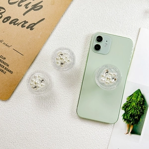 Détail du support de téléphone rond avec perles et strass sur smartphone vert