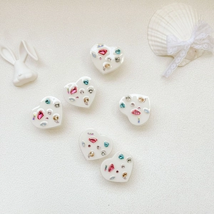 Detailed view of heart-shaped phone grips with colorful rhinestones on white background