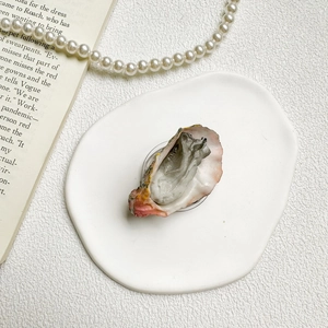 Detailed realistic oyster shell shaped phone socket stand on a decorative ceramic plate