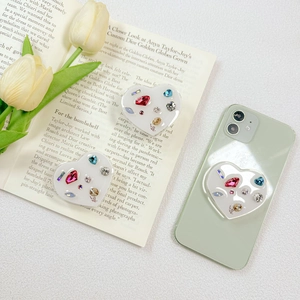 Detail of luxury rhinestone heart phone grip with Love text on a green smartphone