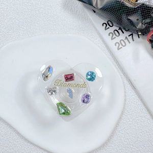 Detail of heart-shaped phone grip featuring colorful rhinestones and gold Diamonds text