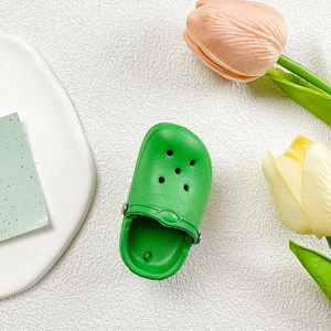 Dettaglio del mini supporto per telefono a ciabatta verde con trama forata realistica