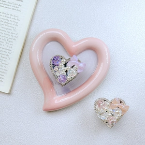 Luxe heart-shaped phone grip with pearls, rhinestones, and butterfly bow on pink dish