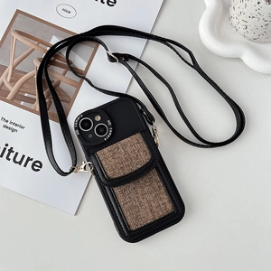 Detail of black crossbody phone case with brown fabric card slot and gold metal hooks