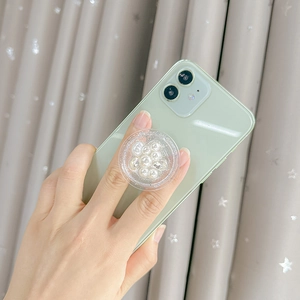 Détail du support de téléphone rond avec perles et strass sur smartphone vert clair