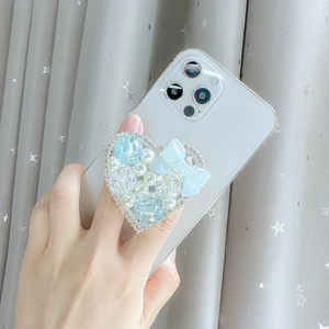 Light blue heart phone grip with pearls, rhinestones and bow on a white smartphone
