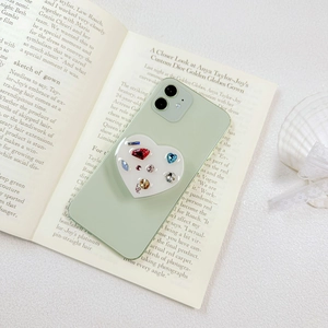 Detail of heart-shaped phone grip with colorful rhinestones and Love text on book