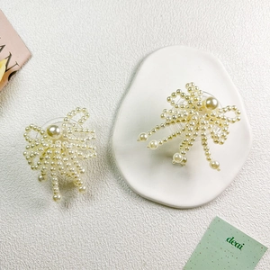 Detail of elegant hand-woven pearl bow phone grip with delicate hanging pearl tassels