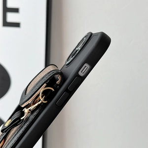 Detail of black leather wallet phone case with gold metal ring and crossbody strap