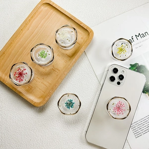 Floral resin phone grip with dried flowers and gold wavy edge on white smartphone