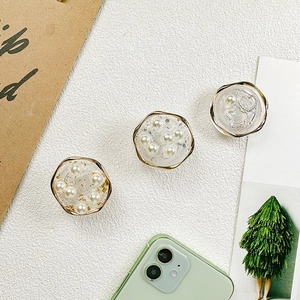 Close-up of heart and pearl gold mobile grips on a smartphone with elegant accessories