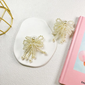 Detail view of handmade pearl bow phone grip on a white ceramic tray with pink book decor