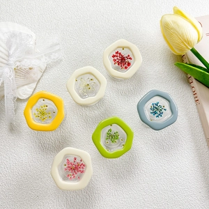 Close-up of hexagonal resin phone grips with pressed dried flowers in various colors
