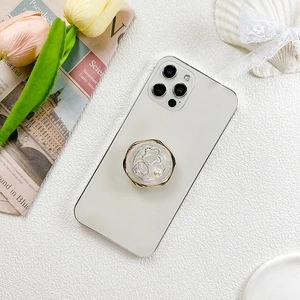 Close-up of heart and pearl phone grip on white smartphone with decorative tulips