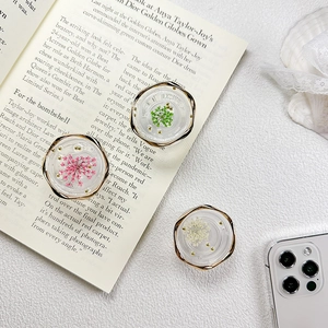 Detailed macro of floral resin phone grips with real dried flowers and gold metal frame