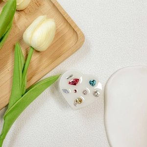 Detail of a white heart phone grip with colorful rhinestones and Love inscription