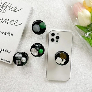 Minimalistisches Handy-Grip-Set mit Edelsteinen und Harz auf einem Smartphone mit Blumen