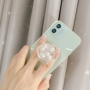Phone grip with golden metal frame, white pearls and glitter star on green smartphone