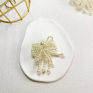 Detail of elegant pearl bow phone grip with hanging tassels on a white decorative tray