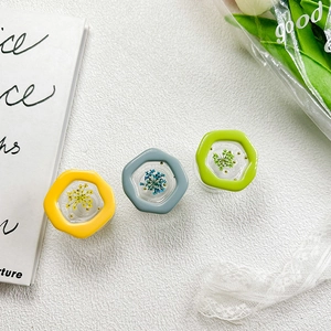 Detail of three hexagonal resin phone grips with real dried flowers in yellow, blue and green